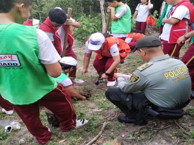 Policía y estudiantes trabajando por mejorar el verde en prado